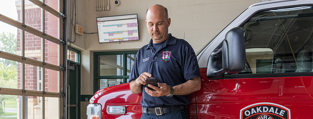 Firefighter using Aladtec software on a mobile device