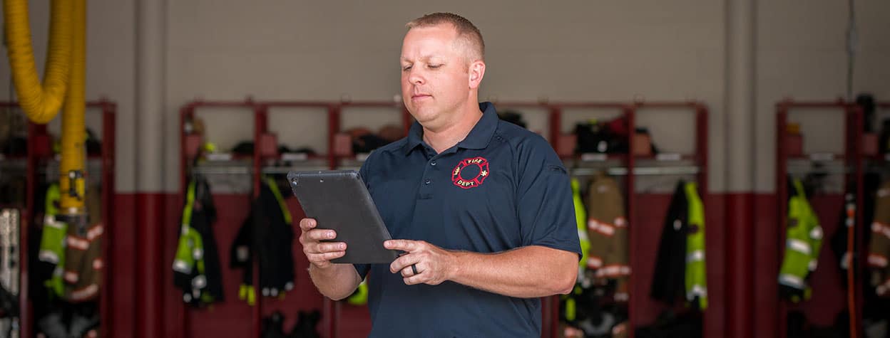 Firefighter using Aladtec software on a mobile device